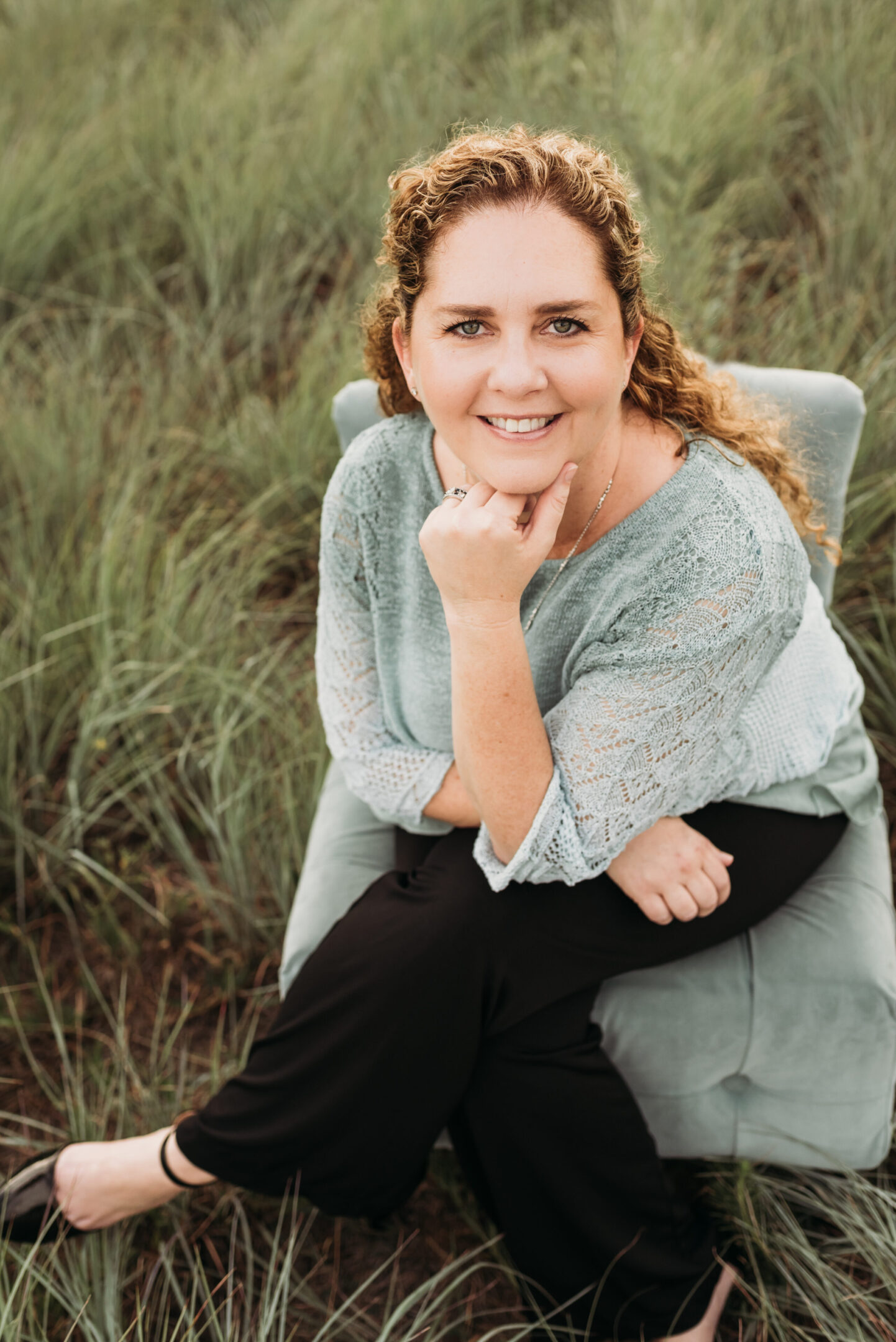 6801af88b389d_headshot cropped A woman sitting on top of a chair in the grass.